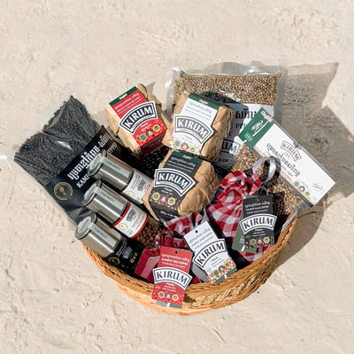 Basket of Kirum Kampot Pepper products - black, white and red pepper in traditional woven packaging, pepper grinders and vacuum-sealed peppercorns