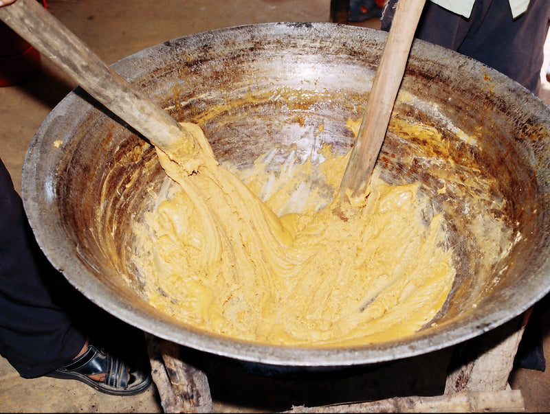 Palm sugar being reduced and stirred in a cooking basin